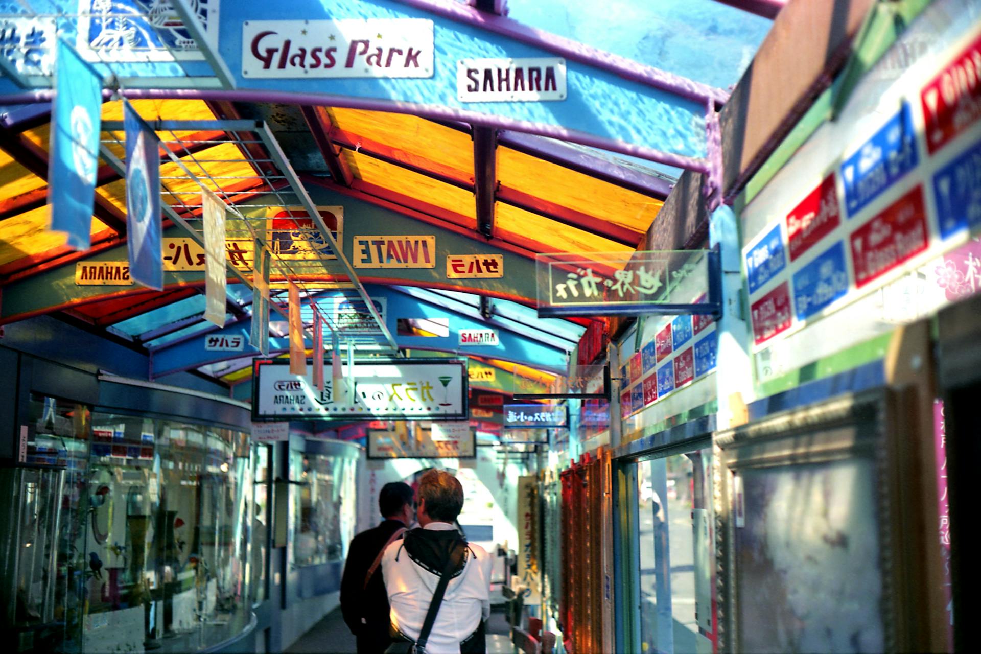 Shoppers walking through a colorful international market arcade with multilingual signage, reflecting global trade, localization, and cross-border ecommerce environments.