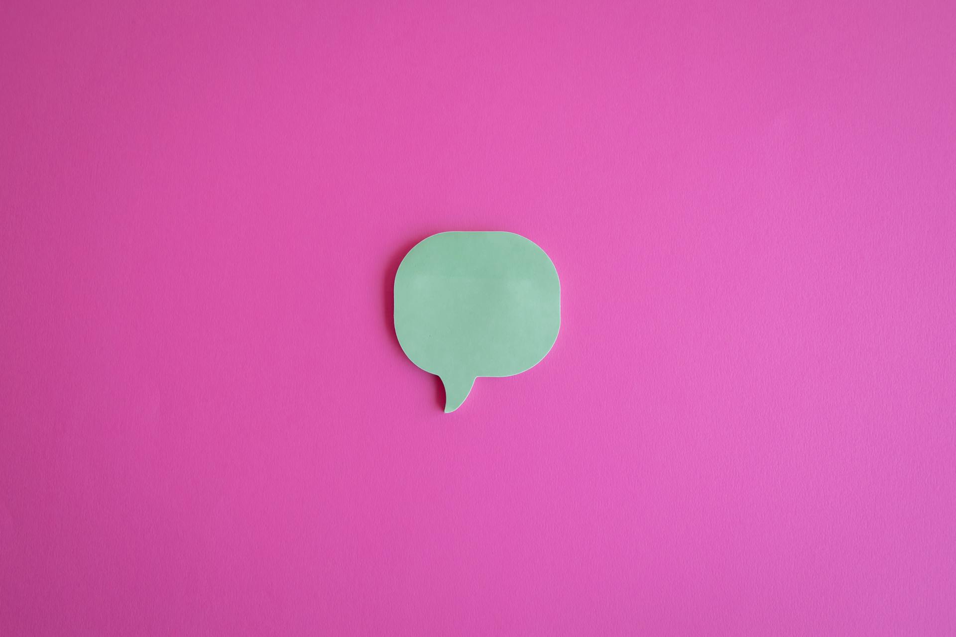 Minimalist green chat bubble on a bright pink backdrop, representing AI-powered customer service automation and digital communication tools.