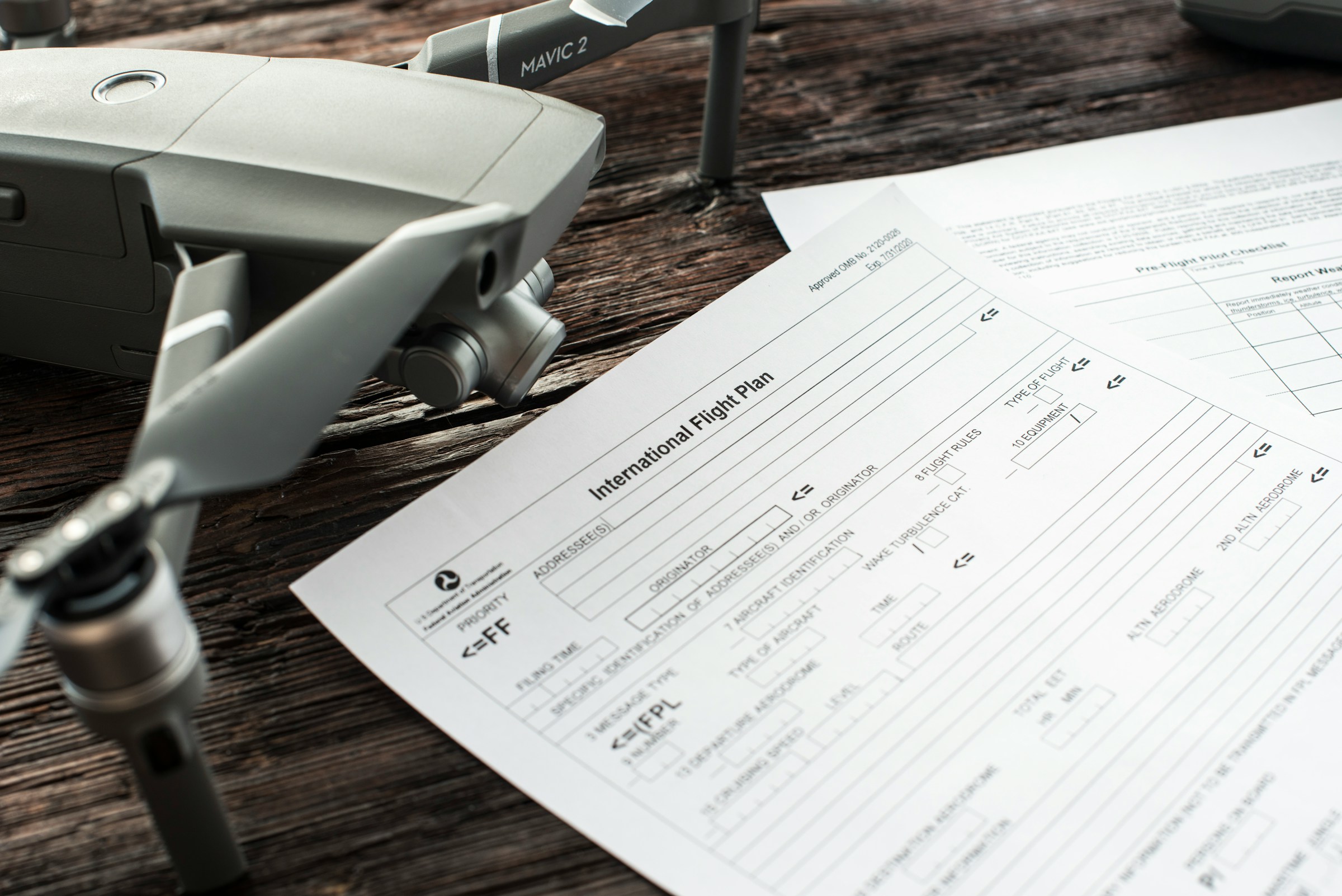 Close-up of an international flight plan document next to a drone, representing international shipping regulations, air freight logistics, and customs documentation for ecommerce shipping.