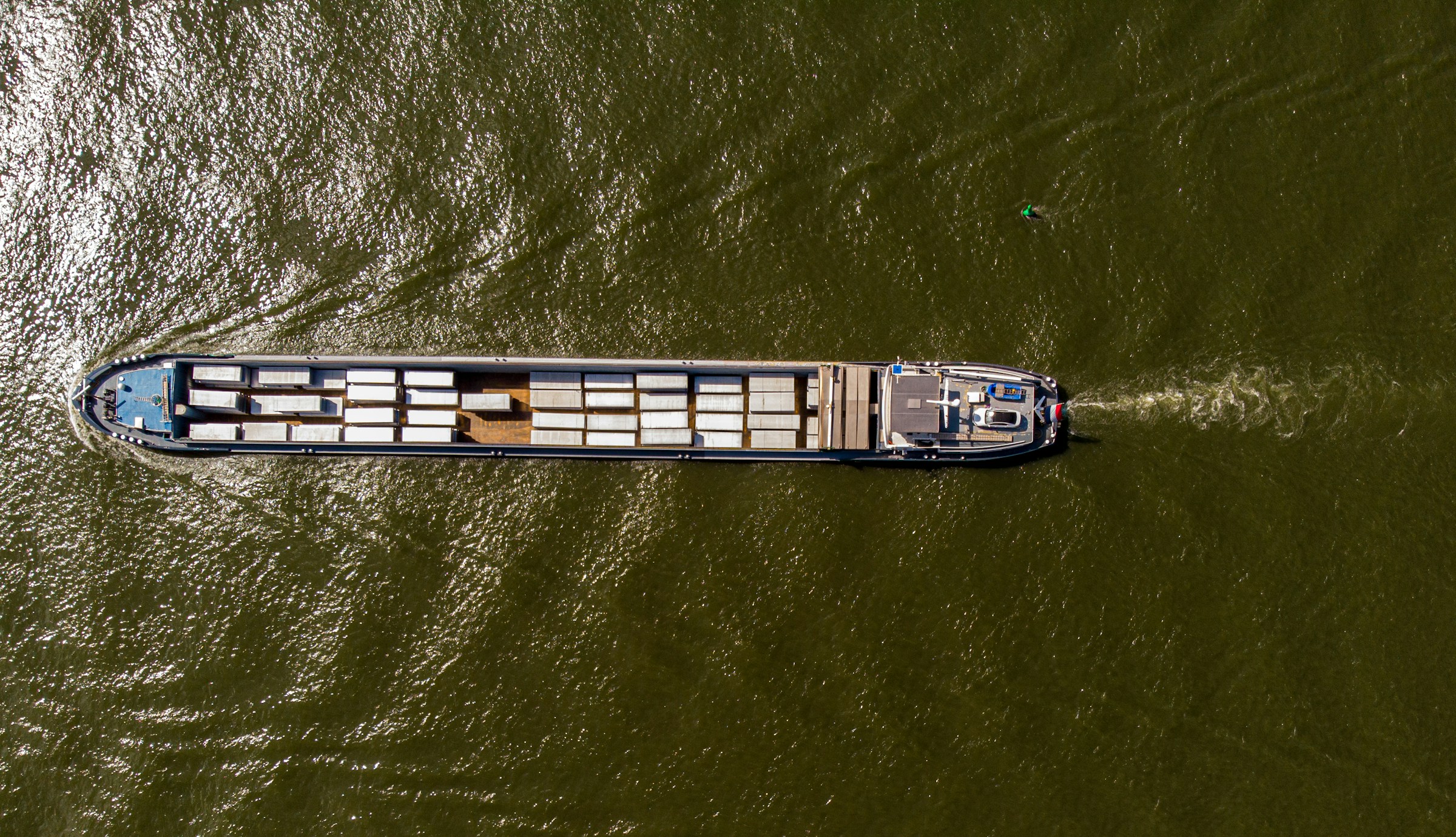 Aerial view of a cargo barge transporting freight containers across water, representing inland shipping and international delivery logistics in ecommerce supply chains.