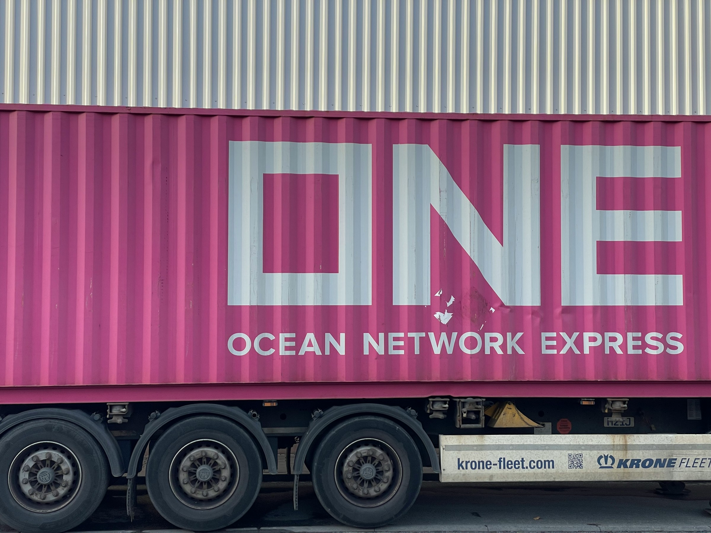 Close-up of a pink Ocean Network Express (ONE) shipping container on a freight truck, representing international shipping, ocean freight logistics, and global ecommerce shipping networks.