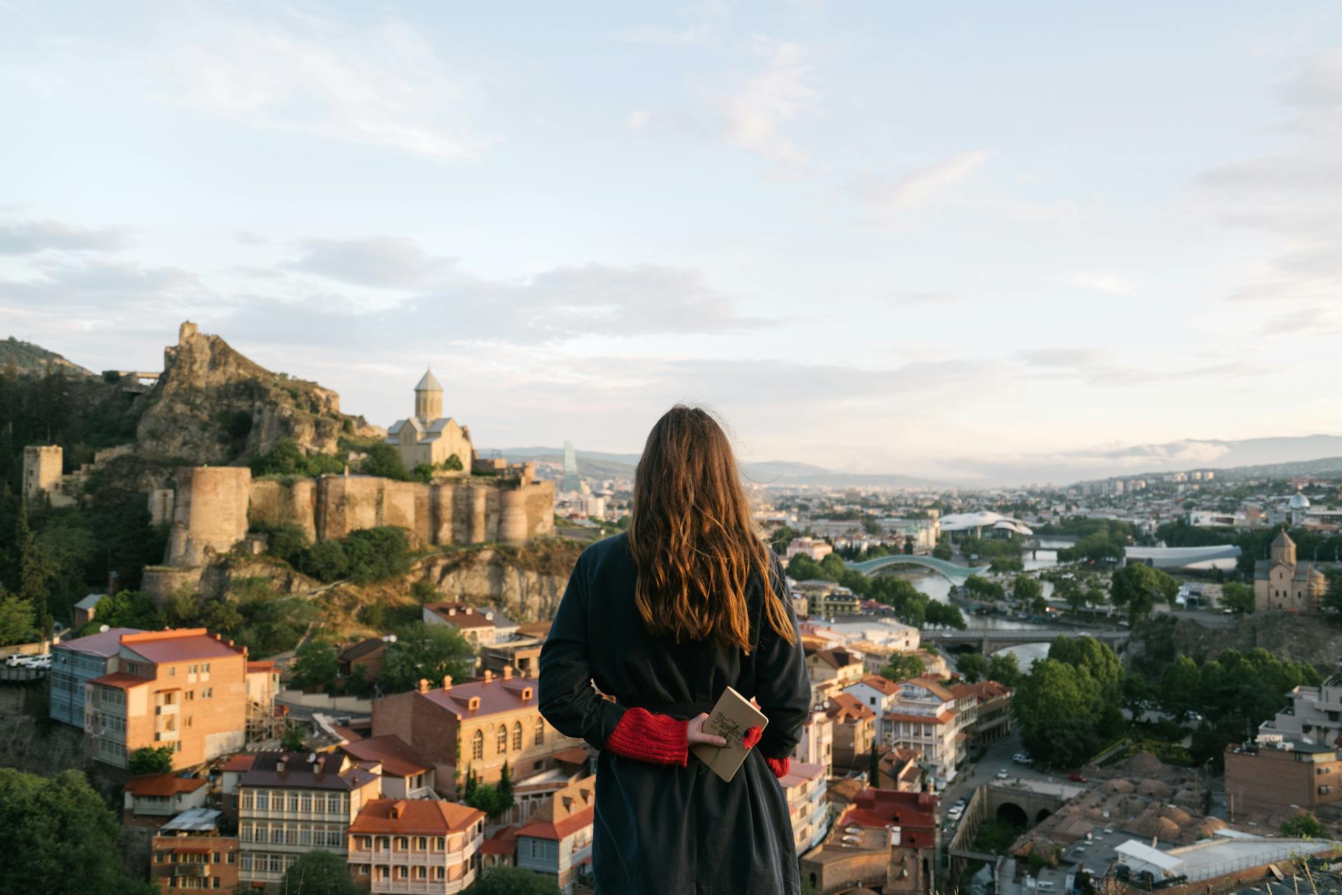 Woman overlooking a historic cityscape with ancient architecture and modern buildings, symbolizing global exploration, international business strategy, and cross-cultural market expansion.