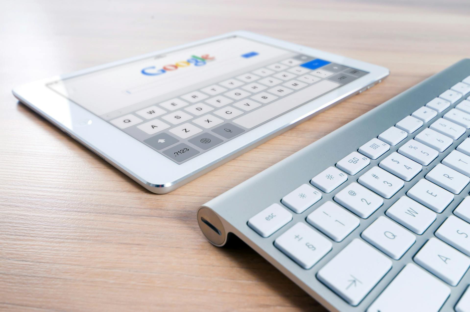 Tablet with Google search open next to a wireless keyboard on a wooden desk, representing digital marketing, search engine optimization (SEO), and online visibility strategies for global audiences.
