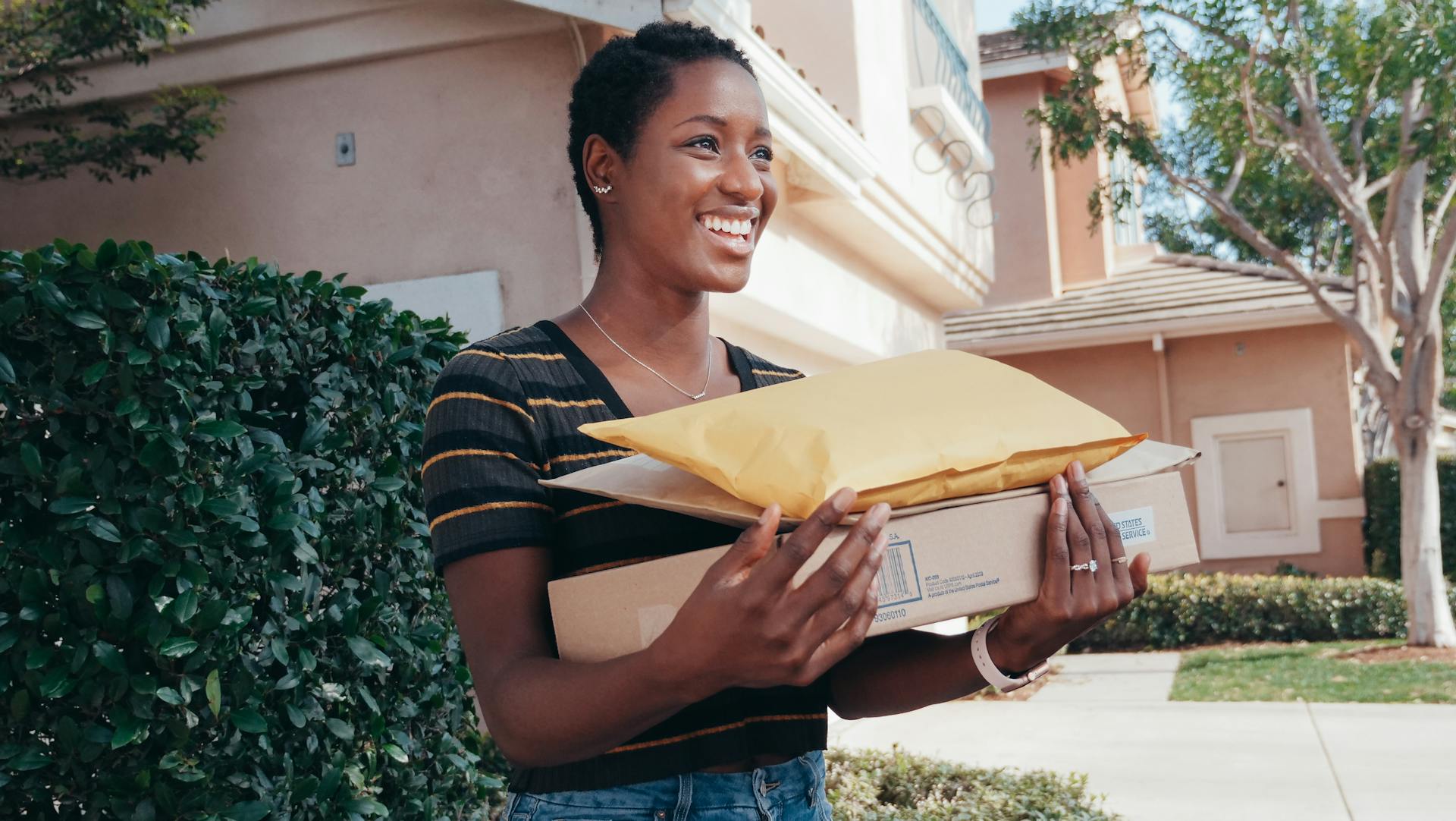 Smiling woman receiving ecommerce delivery packages, representing positive customer experience and efficient order fulfillment.